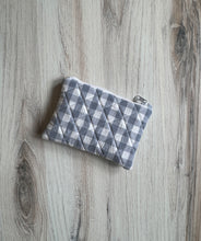 Load image into Gallery viewer, A small quilted fabric pouch with a gray and white gingham pattern, featuring a white metal zipper, resting on a light gray wood-grain surface.